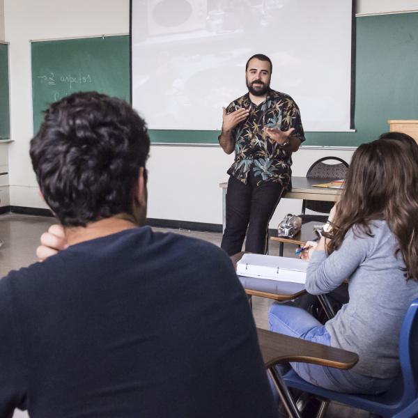 photo of person leaning and conversing with seated students