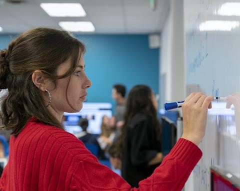 photo of person in red sweater writing on a whiteboard