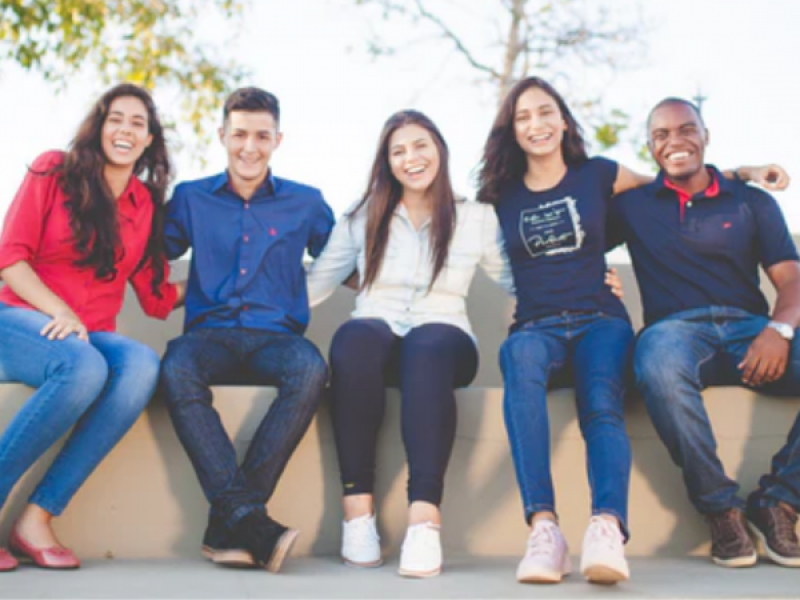 photo of five students sitting on a concrete bench all smiling