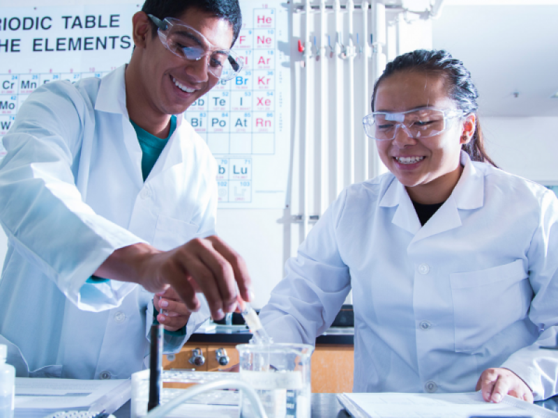 photo of two students in lab coats working on an experiment