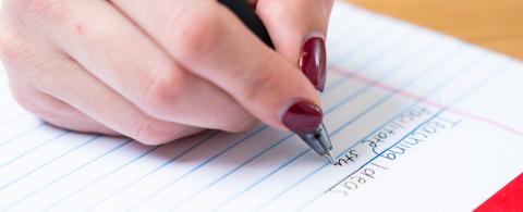 photo of a hand writing on a notepad