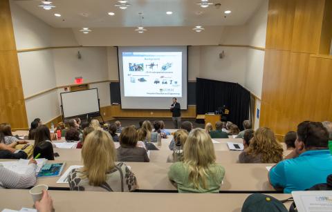 photo of lecture hall taken from the back row looking down over the attendees