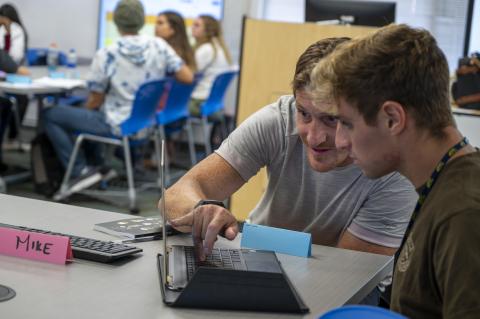 photo of two people looking on one laptop