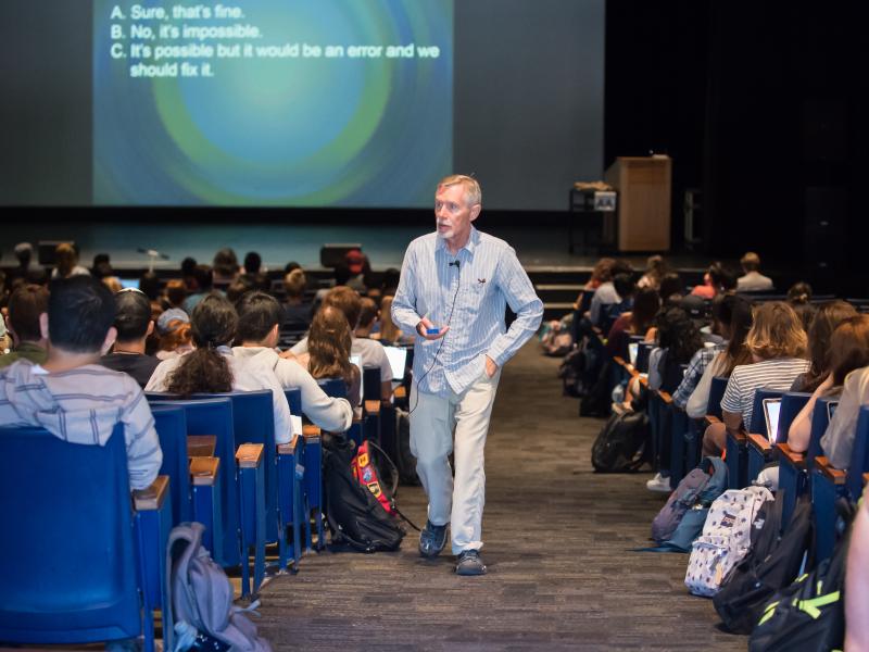 photo of lecturer walking up aisle in lecture hall