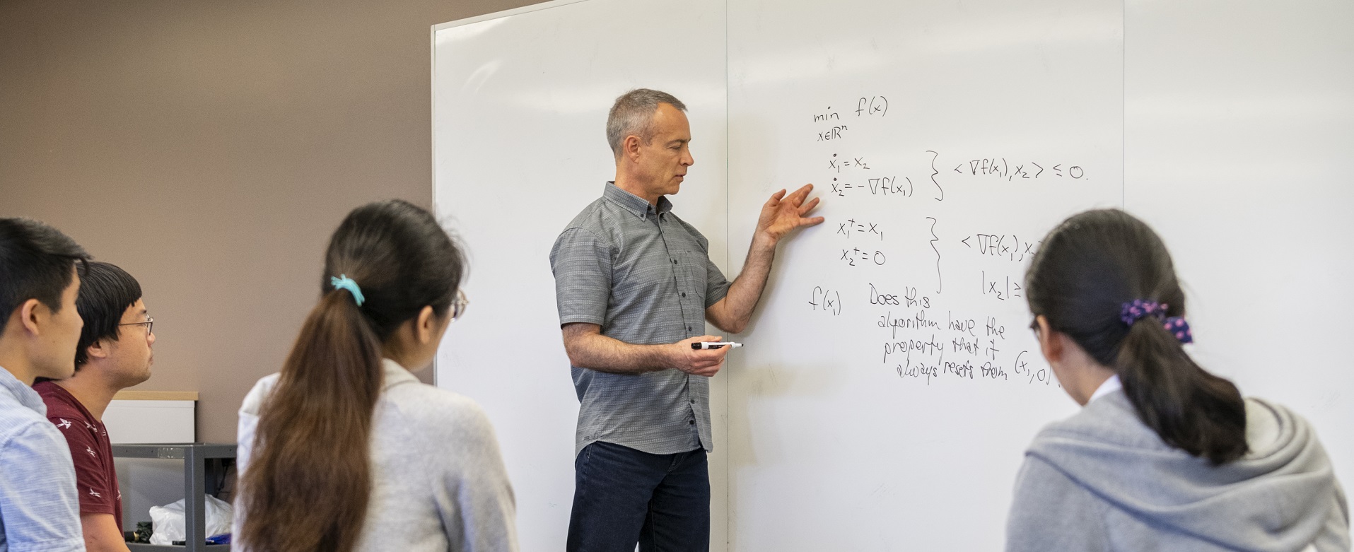 photo of person demonstrating mathematic functions on a whiteboard