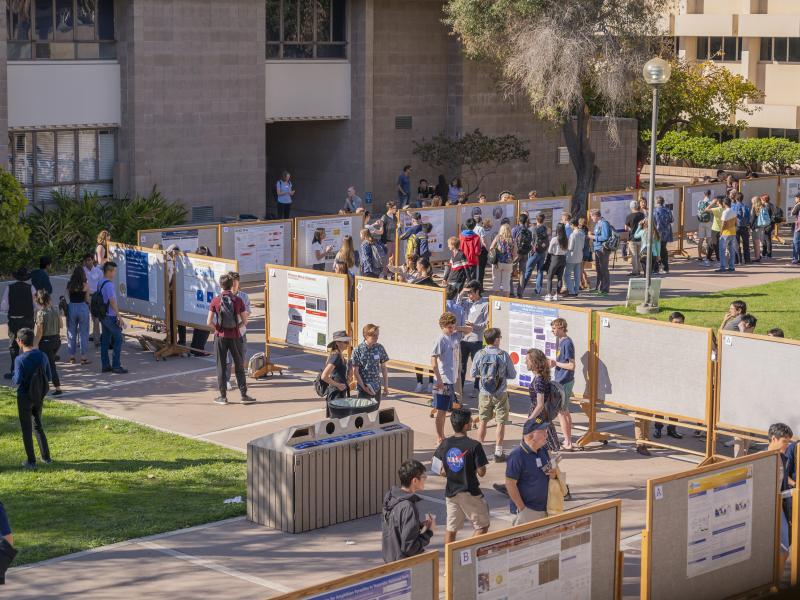 photo with an isometric view of students walking along rows of bulletin boards outside