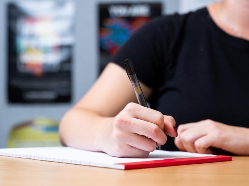 photo of a person writing on a notepad